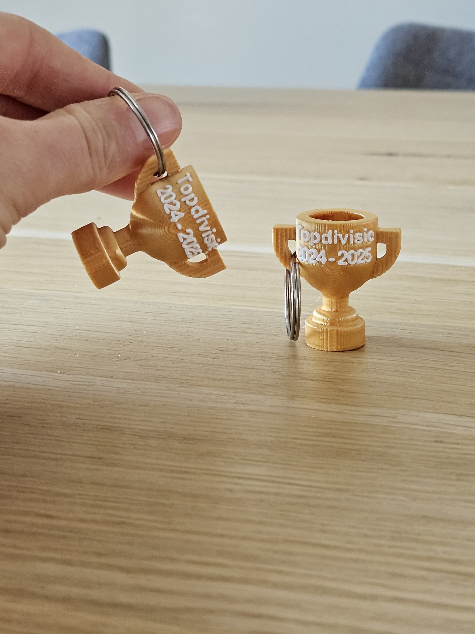 Gepersonaliseerde kampioen sleutelhanger in clubkleuren met naam en jaartal.