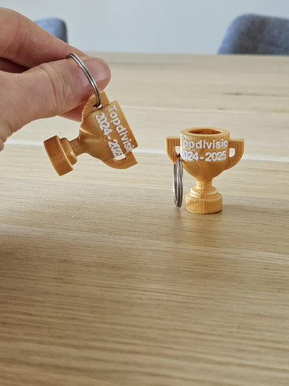 Gepersonaliseerde kampioen sleutelhanger in clubkleuren met naam en jaartal.