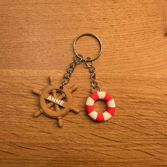 Rood-witte boei en houten stuur sleutelhanger, personaliseerbaar met naam, perfect voor maritieme liefhebbers.