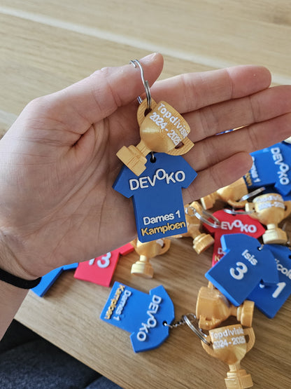Sportieve sleutelhanger in clubkleuren, gepersonaliseerd met tekst of datum.